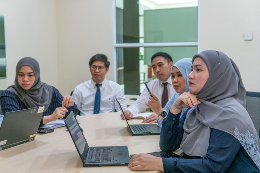 A group of professionals from Brunei Energy Services & Trading Company engaged in a thoughtful discussion during a meeting, with several individuals focused intently on the speaker.