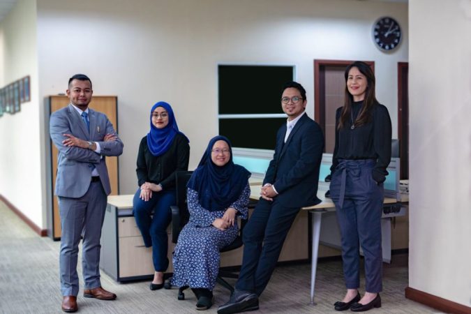 A diverse team of confident professionals, seizing opportunities and posing in a modern office environment, showcases a blend of formal business attire and cultural attire, ready to collaborate and tackle their next project.